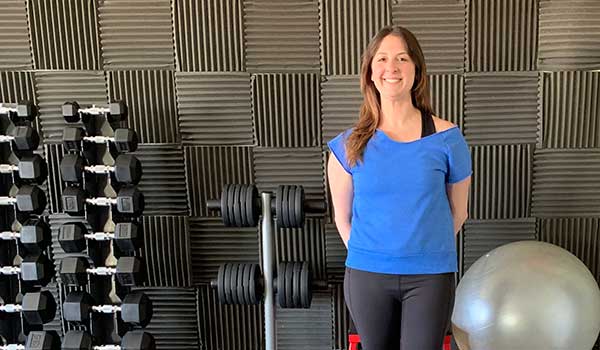 Becca, a female personal trainer in San Francisco, standing in a gym.